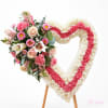 Heart-shaped floral tribute with pink and white flowers on an easel