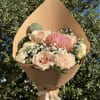 Bouquet of blush roses and pink chrysanthemum wrapped in tan paper