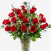 Tall arrangement of red roses with filler blooms in a clear glass vase