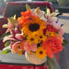 Bright mixed bouquet in a white vase with roses, lilies, sunflowers, and carnations