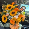 Fall bouquet in a pumpkin vase with sunflowers, roses, and orange blooms