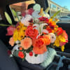 Bouquet in a white pumpkin vase with orange roses, yellow mums, and white lilies