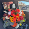 Bouquet of roses, lilies, and mums in a pumpkin vase with a red bow