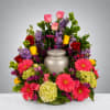 Colorful funeral urn surround with roses, gerberas, and hydrangeas