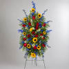 Standing floral spray with red roses, sunflowers, and blue flowers on a metal easel