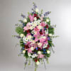 Standing floral spray with pink lilies, white roses, and daisies on an easel