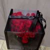 Red roses arranged in a black gift box with a satin ribbon