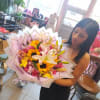 Woman holding a large bouquet of lilies, sunflowers, and pink roses