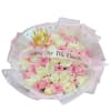 Round bouquet of pink and white roses wrapped in pink-edged paper with a gold crown decoration