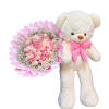 Pink and cream rose bouquet beside a white teddy bear with a pink bow