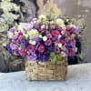 Mixed pink, purple, and white flowers in a woven basket