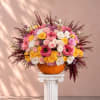 Mixed pink, white, and yellow flowers arranged in a pumpkin vase