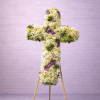 Tall floral cross of white and cream flowers with lavender accents on a wooden easel