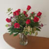 Arrangement of red roses with small white and pink filler flowers in a clear glass vase