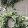 Pair of lush eucalyptus wreaths hanging on a light-colored wall