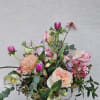 Loose arrangement of pink and peach blooms, including roses and tulips, in a clear glass vase