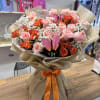 Bouquet of pink and orange roses with baby’s breath in tan wrap