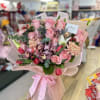 Pink rose and orchid bouquet wrapped in pale pink paper with a ribbon