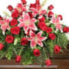 Red roses and pink lilies arranged on a wooden casket