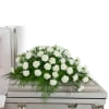 White floral spray arranged on top of a casket
