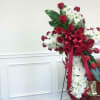 Standing funeral spray of red roses and white daisies with a ribbon