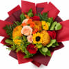 Bouquet of red, orange, and peach flowers wrapped in red paper