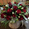 Red rose arrangement in a rustic white vase