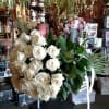 Large bouquet of white roses with green leaves and white ribbon