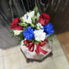 Bouquet of red roses, white alstroemeria, and blue carnations tied with a red ribbon