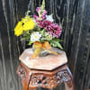 Small mixed flower bouquet in a clear glass vase with an orange ribbon