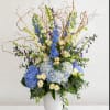 Tall blue and white floral arrangement in a white vase with curly branches