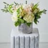 White and pale peach floral arrangement in a silver vase