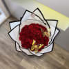 Bouquet of red roses wrapped in white paper with black trim and gold butterfly accents