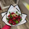 Red roses arranged in a white and black wrapped bouquet with a gold "I love you" topper