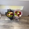 Two wrapped bouquets with red, white, and yellow flowers on the floor.