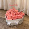 Pink roses arranged in a heart-shaped box with a clear topper