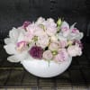 Pink roses and white orchids arranged in a white bowl vase