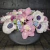 Pink orchids and white anemones arranged in a dark bowl
