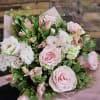 Pink roses and white blooms in a hand-tied bouquet with pink wrap