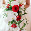 Bride holding a bouquet of red roses and white orchids