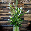 White calla lilies in a clear glass vase with tall grass accents