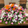 Large casket spray of pink roses, orange lilies, and white orchids.