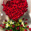 Heart-shaped red rose display with tiara above a base of red roses, white lilies, and yellow filler flowers.