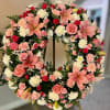 Standing wreath of pink lilies, roses, and mixed white and pink flowers on an easel