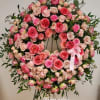 Large pink and peach rose wreath with satin bow displayed on a metal easel