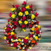 Circular wreath of red and yellow roses with mixed orange and white flowers in a dense design