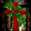 Tall standing cross of red roses with bold green leaves on an easel