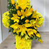 Yellow cross-shaped sympathy arrangement with lilies, roses, and chrysanthemums on a wooden stand