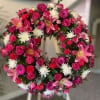 Standing wreath of pink lilies, roses, gerbera daisies and white chrysanthemums on an easel