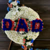 Standing sympathy wreath with white mums and blue and red flowers spelling DAD on an easel
